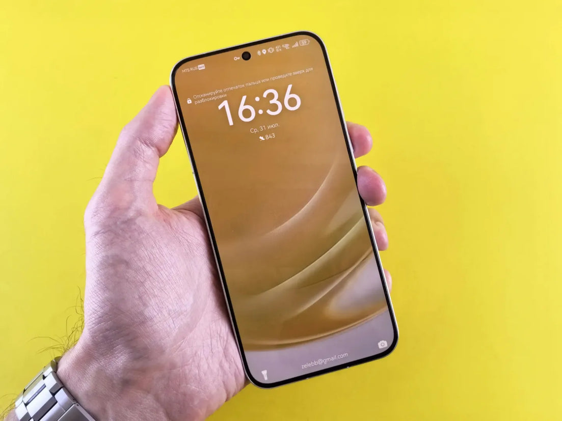 a mobile phone in hand on yellow background showing time