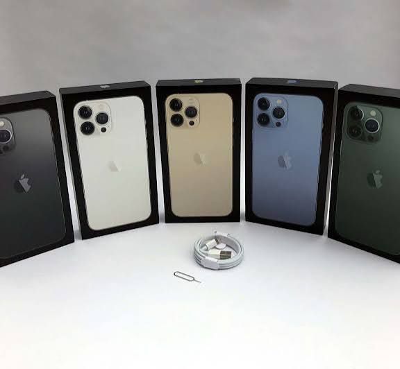 Five Apple iPhones in their boxes on a white surface with a small ring in front.