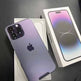 Purple iPhone 12 Pro Max on a dark surface with its box.