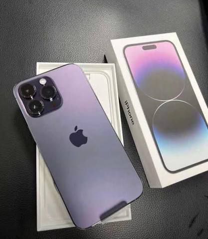 Purple iPhone 12 Pro Max on a dark surface with its box.