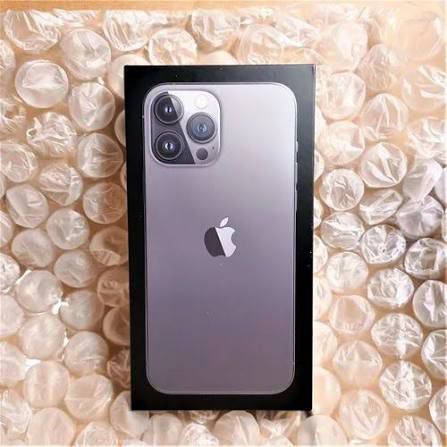 Silver iPhone 11 Pro Max in packaging on a textured beige surface