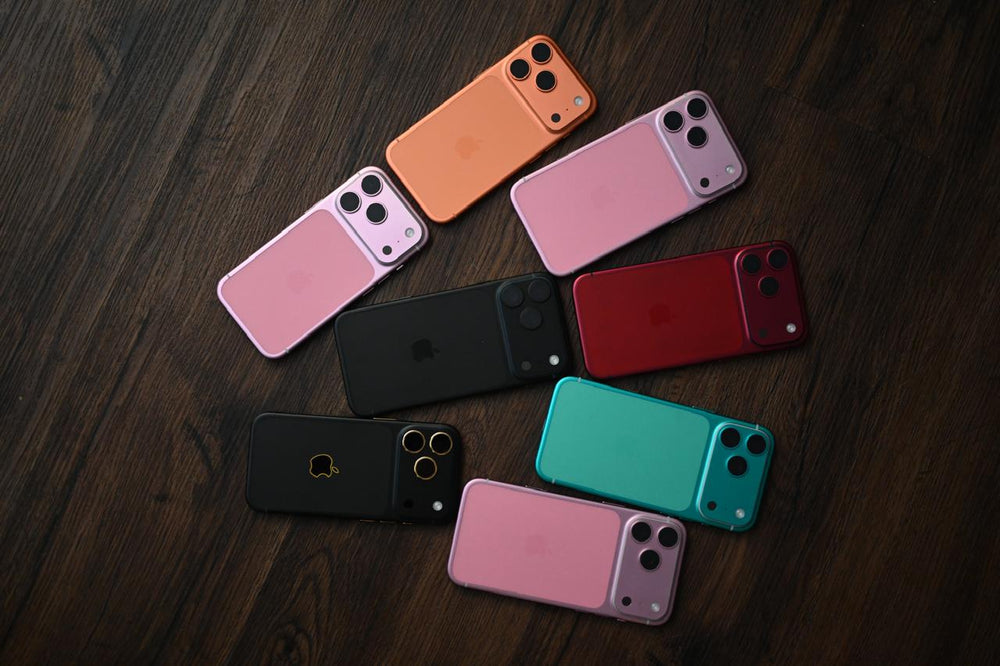 Multiple smartphones in various colors arranged on a wooden surface