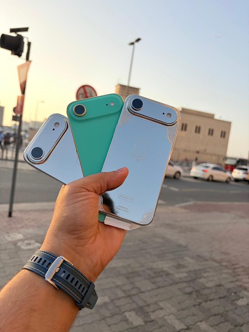 Three smartphones held in a hand with a blurred street background